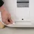 Hand showing connection of a mains plug to the automatic cat toilet. Product details and CE marking visible on the back.