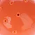 Balle orange en plastique avec plusieurs trous visibles à la surface, vue rapprochée du jouet sans marque ni texte apparent.