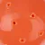 Gros plan sur une surface orange en plastique avec plusieurs trous ronds visibles, sans marque ni texte apparent.