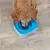 Cane che beve da una ciotola d'acqua blu con protezione dagli schizzi su pavimento in legno.