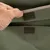 Primer plano de material textil verde con cierre de velcro, abierto por una mano.
