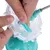 Ruka pokazuje umetanje zelenog plastičnog klipa u prozirni uređaj. Prikaz montaže igračke ili dodatka.