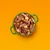 Schüssel mit Fleischstücken, Karotten und Nudeln in Soße, präsentiert auf orangefarbenem Hintergrund.