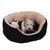 Hund med sort og hvid pels ligger i rund, sort hundeseng med beige inderside. Materialet ser blødt ud, og kanten har en gylden snor.