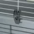 Schwarzer Kunststoffclip zur Befestigung an einem grauen Metallkäfig mit weißen Gitterstäben.