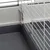 Vue rapprochée d’un coin de cage pour petits animaux, avec base en plastique gris et grille métallique blanche. Système d’attache visible entre la base et la grille.