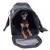 Petit chien assis dans un sac de transport noir à bandoulière, ouverture avant zippée et surface intérieure en tissu, parties latérales avec motif à carreaux rouges visibles.
