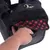 Sac noir avec poche avant ouverte, doublure intérieure à motif rouge et noir, main insérant un objet dans la poche. Fermeture éclair métallique visible en haut.