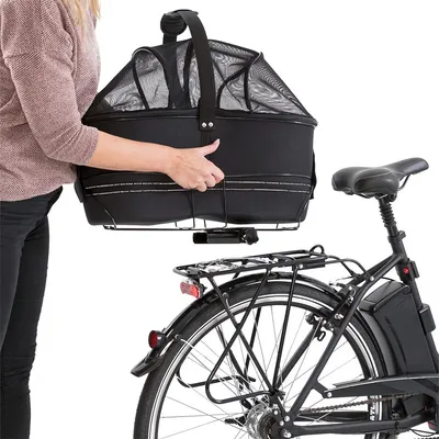 Cestino nero con rete per pet, trasportato da una persona e posizionato su portapacchi posteriore di una bicicletta. Cestino nero con rete per pet, trasportato da una persona e posizionato su portapacchi posteriore di una bicicletta.