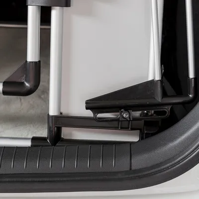 Close-up of a metal and plastic locking mechanism on a pet transport crate, showing secure attachment to the vehicle interior.
