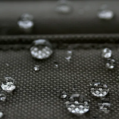 Lähikuva vettä hylkivästä kankaasta, jonka pinnalla on vesipisaroita.