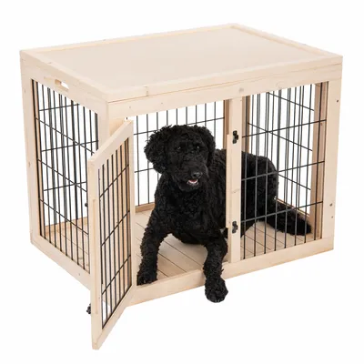 Niche ou cage pour chien en bois clair avec barreaux métalliques noirs, porte ouverte, chien noir à l’intérieur. Matériaux visibles : bois et métal.