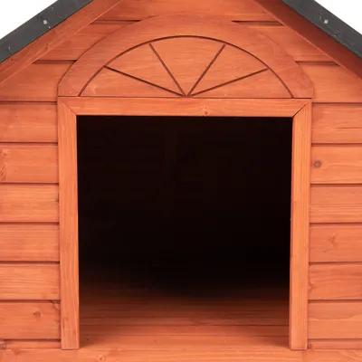 Houten hondenhok met gebogen ingang en donkere binnenruimte, geschikt voor buitengebruik.