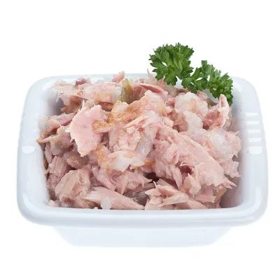 Ciotola bianca con carne sminuzzata rosa e bianca, decorata con un rametto di prezzemolo verde. Nessun marchio o testo visibile.