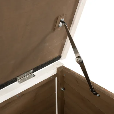 Charnière et bras en métal visibles sur le couvercle ouvert d’un coffre ou abri en bois, fixation par vis apparente, intérieur brut sans marquage ni texte visible.