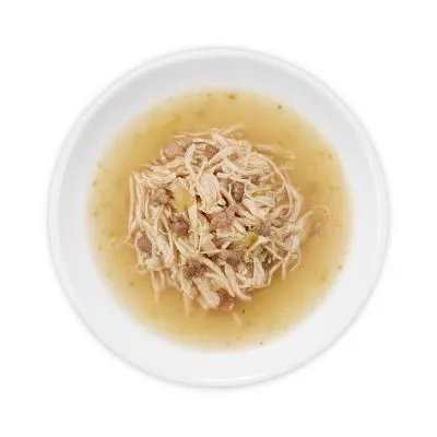 Wit keramisch schaaltje met natvoer bestaande uit stukjes vlees in gelei of bouillon, zonder zichtbare merknaam of verpakking.