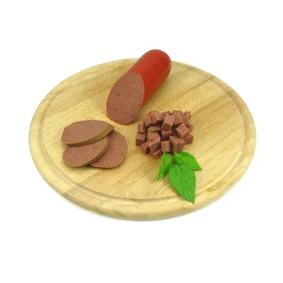 Колбас за домашни любимци, нарязан на шайби и кубчета, поднесен върху дървена дъска с листа от билка. Видими са различни форми на продукта.