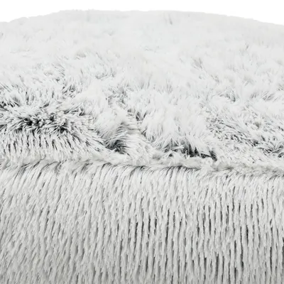 Detalle de superficie de cama para mascotas con tejido de felpa blanca y textura mullida visible en primer plano.