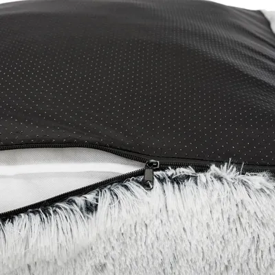 Detalle de cama para mascotas con base antideslizante negra, cremallera visible y borde de tela tipo peluche gris y blanco.