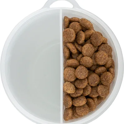 Round plastic box with two compartments, one empty and the other filled with brown dry food pieces.
