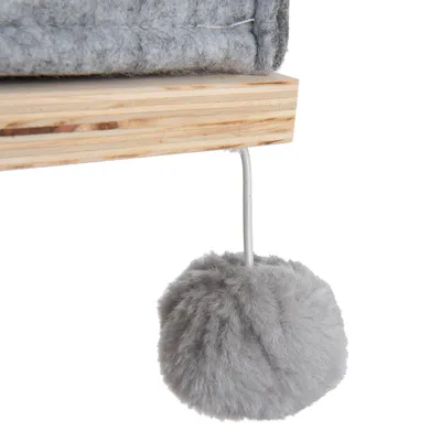 Grauer Plüschball an einer Schnur, befestigt an einer Holzplattform mit grauem Stoffbezug.