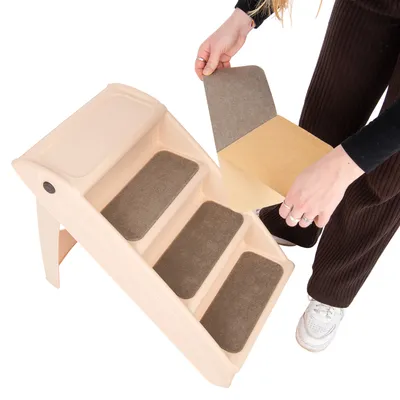 Beige Treppe mit drei Stufen, Person befestigt braune rutschfeste Matten auf den Stufen.