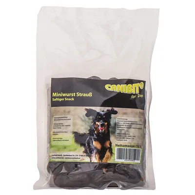 Пакет с кучешки лакомства CANIBIT Miniwurst Strauß Saftiger Snack, нетно тегло 185 г. Етикетът е на немски език и показва снимка на черно-кафяво куче.