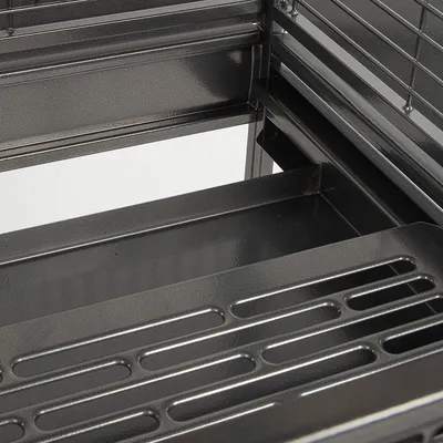 Gros plan sur le fond d'une cage en métal noir avec grille et bac amovible visible, sans accessoires ni animaux.