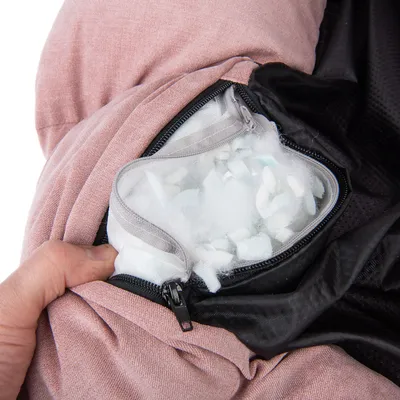 Lynlås åbnet på lyserødt betræk, der viser indvendig pude med fyld af skumstykker og vat. Synlige materialer: stof, lynlås, skumfyld.