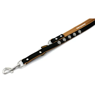 Schwarze Hundeleine mit brauner Unterseite, silbernen Schneeflocken-Verzierungen und Metallkarabiner. Text sichtbar: 'Made in Germany'.
