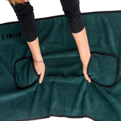 Grüne Hundetrockendecke mit zwei integrierten Handtaschen, gezeigt in der Anwendung durch Hände. Markenname 'DOG' sichtbar auf der Decke.