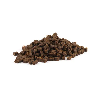 Petits morceaux de friandises brunes pour animaux, présentés en tas sur fond blanc. Aucun emballage ni marque visible.