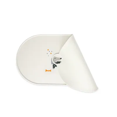 Bílá podložka pod misku s motivem spícího psa, oranžovou kostí a hvězdami. Zobrazeno napůl srolované.