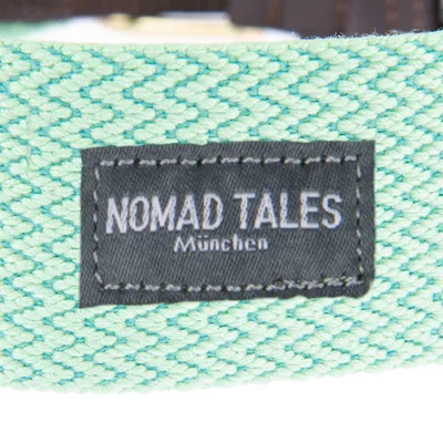 Nomad Tales München. Ετικέτα μάρκας σε πράσινο ύφασμα με υφαντό μοτίβο.