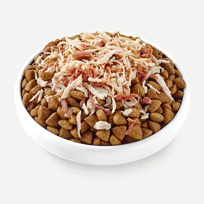 Bowl with brown dry food pieces, topped with shredded chicken and duck meat.