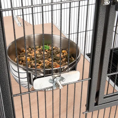 Gamelle en métal avec mélange de graines, fixée à une grille de cage. Convient pour nourrir les petits animaux ou les oiseaux.