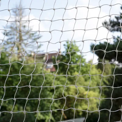 Close-up de uma rede de proteção branca com fundo de jardim verde, adequada para fins de segurança.