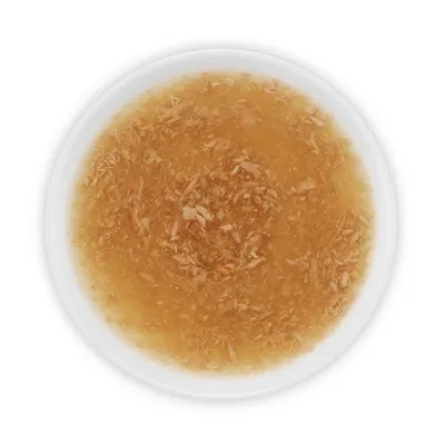 Contenu d’une assiette blanche avec bouillon brun clair et morceaux visibles, vue du dessus. Aucun emballage ou marque visible.