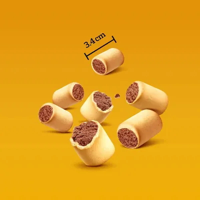 Friandises fourrées pour animaux, forme cylindrique, diamètre 3,4 cm indiqué sur l’image. Intérieur marron visible, extérieur beige clair.