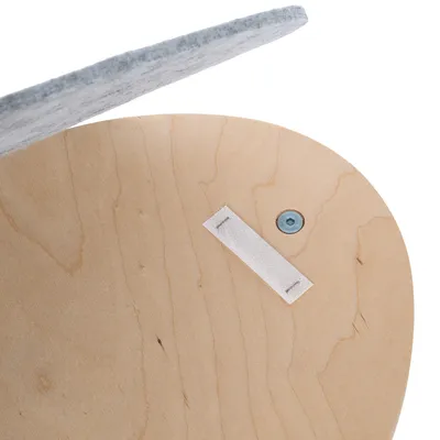 Vue rapprochée d’une surface en bois clair avec une vis métallique et une bande auto-agrippante blanche fixée, partie supérieure recouverte de feutre gris visible.