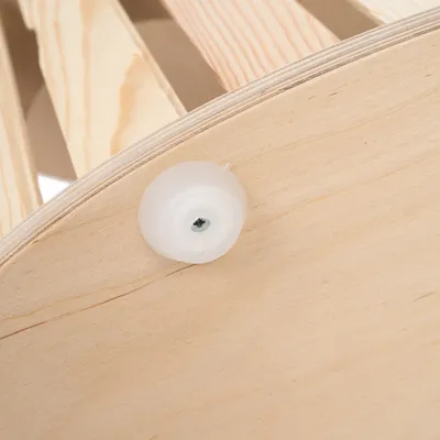 Détail d’une structure en bois clair avec patin en plastique blanc fixé par une vis métallique.