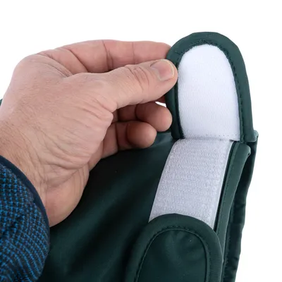 Primo piano di una mano che apre un tessuto verde con chiusura a strappo. Mostra la funzione della chiusura.