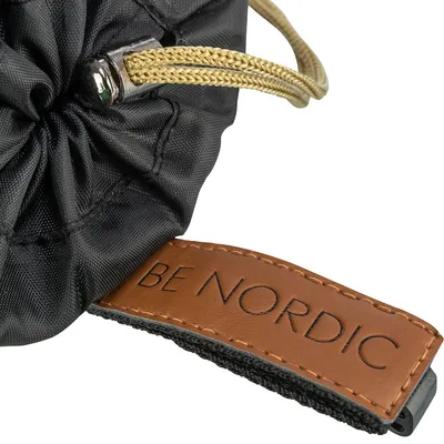 Nærbillede af et Be Nordic produkt med brunt lædermærke, sort stof og gul snor.