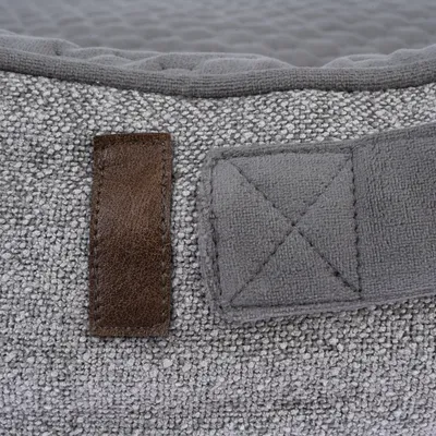 Detailaufnahme eines grauen Stoffmaterials mit braunem Lederakzent und verstärkter Naht. Geeignet für Produktbeschreibung oder Materialdarstellung.