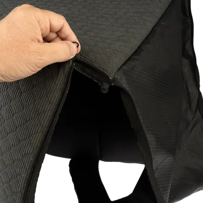 Primo piano di una cerniera nera su una copertura imbottita in tessuto, aperta da una mano.