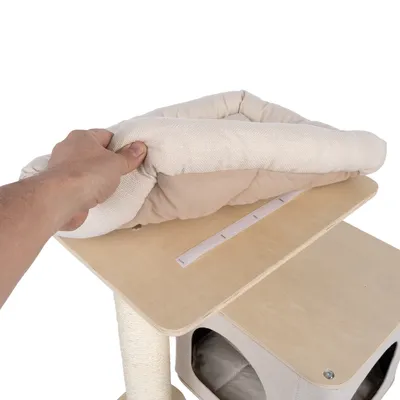 Mano muestra cojín extraíble y acolchado con cierre de velcro sobre una plataforma de madera de un árbol rascador.