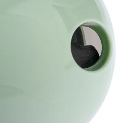 Detalj okruglog predmeta od zelene plastike s otvorom i crnim unutarnjim dijelom, bez vidljivih oznaka ili brenda.