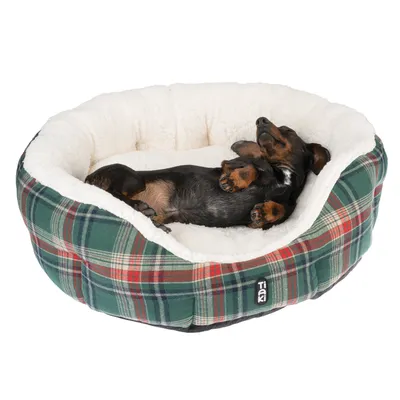 Hund schläft in einem weichen, karierten Hundebett mit weissem Innenfutter. Markenlogo Trixie sichtbar auf der Aussenseite des Bettes.