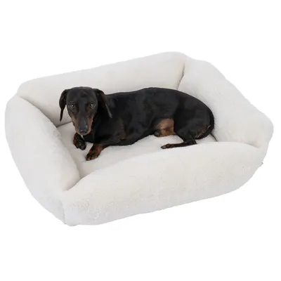 Dog lying in a white, fluffy pet bed. Product shows the comfort and design of the bed.