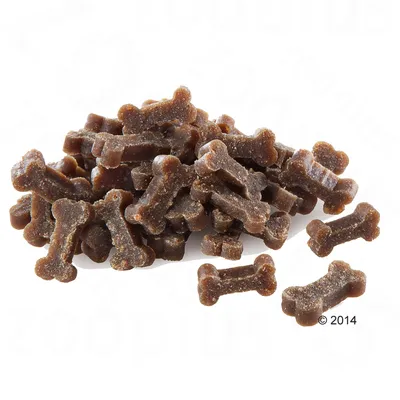 Friandises pour chien en forme d’os, couleur brune, présentées en tas sur fond blanc. Aucun emballage ou marque visible.